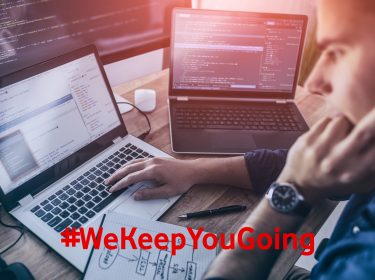 Ein Mann programmiert am Laptop und mit mehreren Bildschirmen.