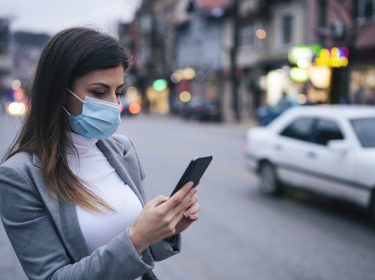 Frau mit Smartphone und Maske