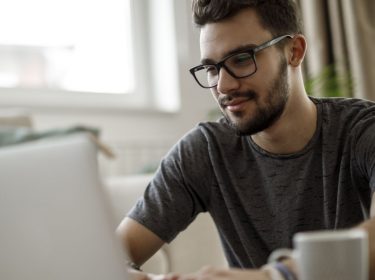 Mann sitzt am Laptop