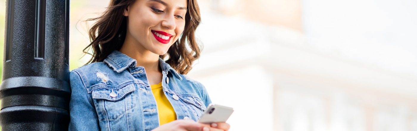 Frau mit Smartphone an Laterne