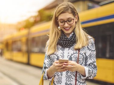 Junge Frau surft unter iOS 14 am iPhone.