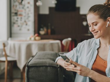 Frau mit Smartphone und AirPods