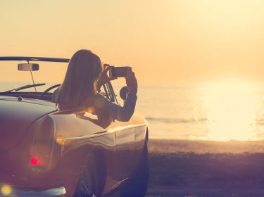 Frau fotografiert aus dem Auto den Sonnenuntergang
