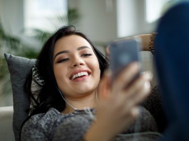Frau streamt am Smartphone Musik mit Spotify.