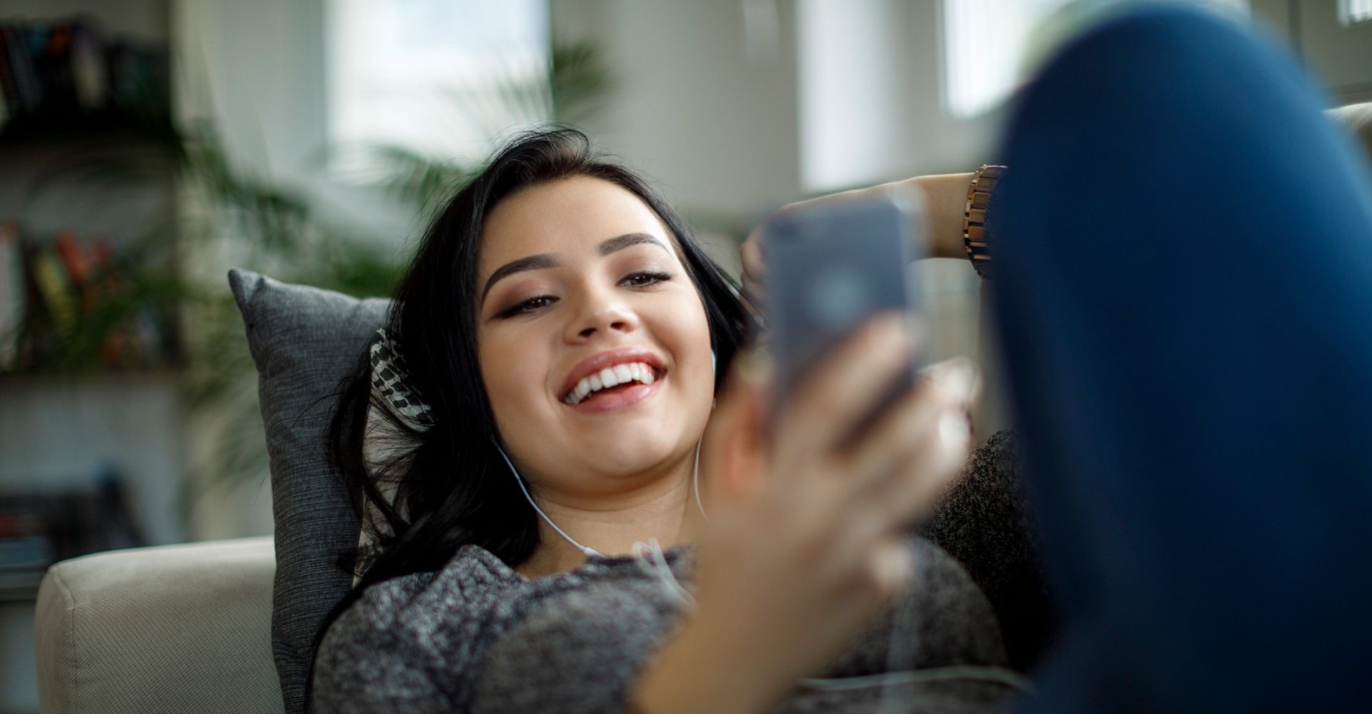 Frau streamt am Smartphone Musik mit Spotify.