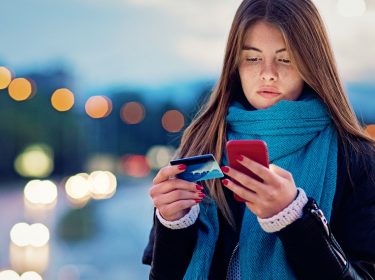 Frau richtet Google Pay mit Smartphone und Kreditkarte ein.