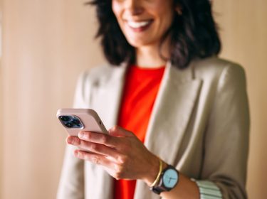 Eine Frau im Office-Look interagiert mit einem iPhone.