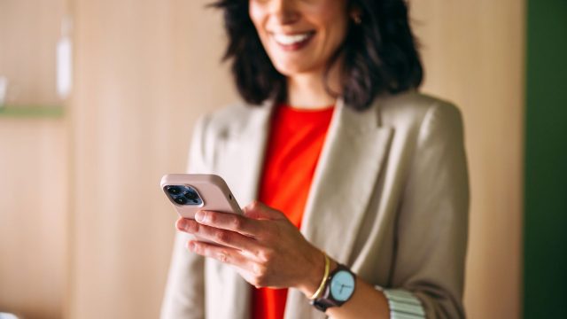 Eine Frau im Office-Look interagiert mit einem iPhone.