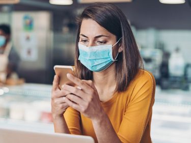 Frau sieht am Smartphone die Corona-Karte von Google ein