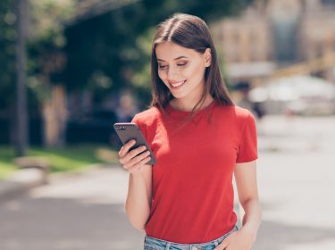 Junge Frau schaut auf ihr Android-11-Gerät.