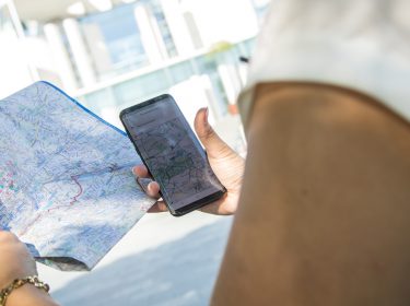 Frau hält Smartphone und Karte