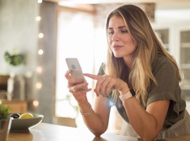 Frau nutzt Smartphone in der Küche