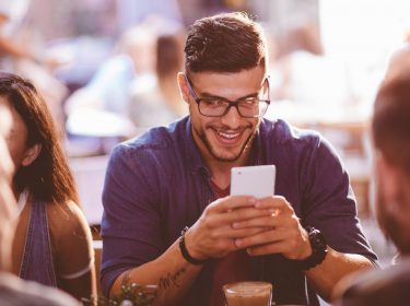 Mann sendet Geld per PayPal mit dem Smartphone