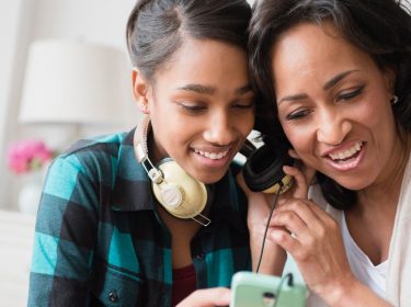 Mutter und Tochter hören Musik über Smartphone
