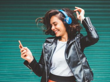 Frau auf grünem Hintergrund hört Musik.