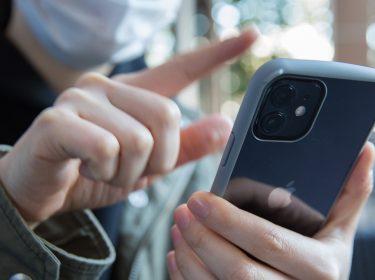 Frau wischt mit Finger auf iPhone 12