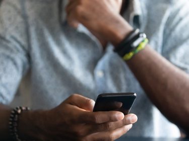 Grübelnder Mann hält Smartphone in der Hand