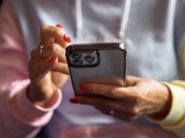 Junge Frau tippt auf ihr iPhone.