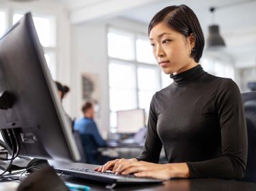Frau arbeitet im Büro am PC