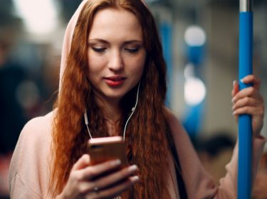 Frau hört Musik am Handy via Spotify.