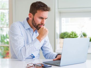 Mann sitzt konzentriert an seinem Laptop