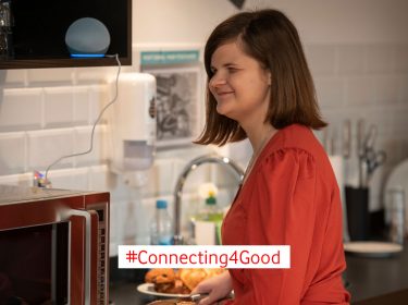 Eine Frau bereitet etwas in der Küche zu und hört einer Audiodeskription über ihr Alexa-Gerät zu.