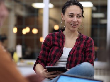 Frau hält Tablet in einem Meeting