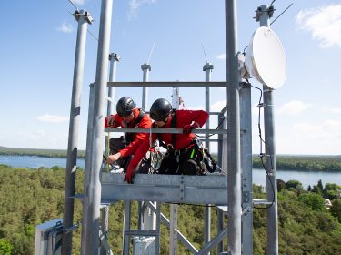 Vodafone-Techniker:innen montieren 5G-Antennen auf einer Mobilfunk-Station in Berlin.