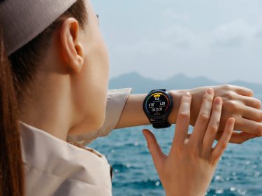 Frau am Strand guckt auf Huawei Watch 3 in Schwarz