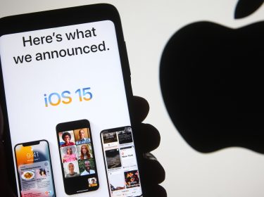 Hand hält iPhone mit iOS 15 vor Apple-Logo