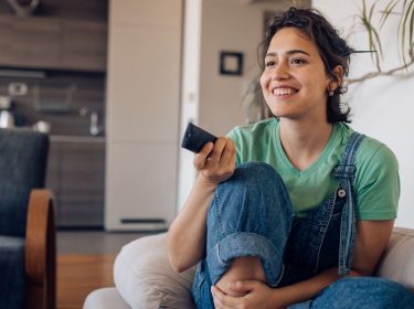 Frau mit Fernbedienung auf dem Sofa
