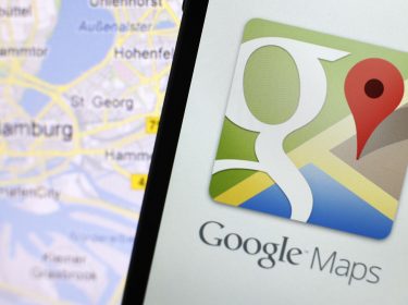 Google-Maps-App auf einem Smartphone neben einer Karte