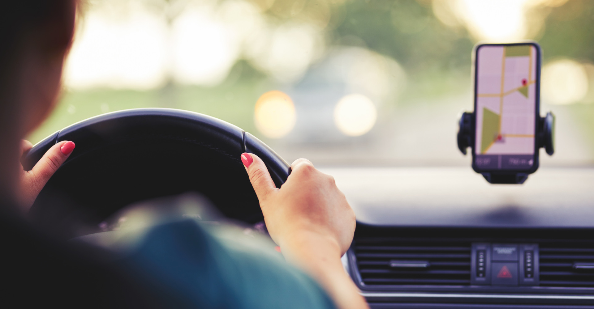 Frau fährt mit dem Auto, nutzt Google Maps auf dem Handy