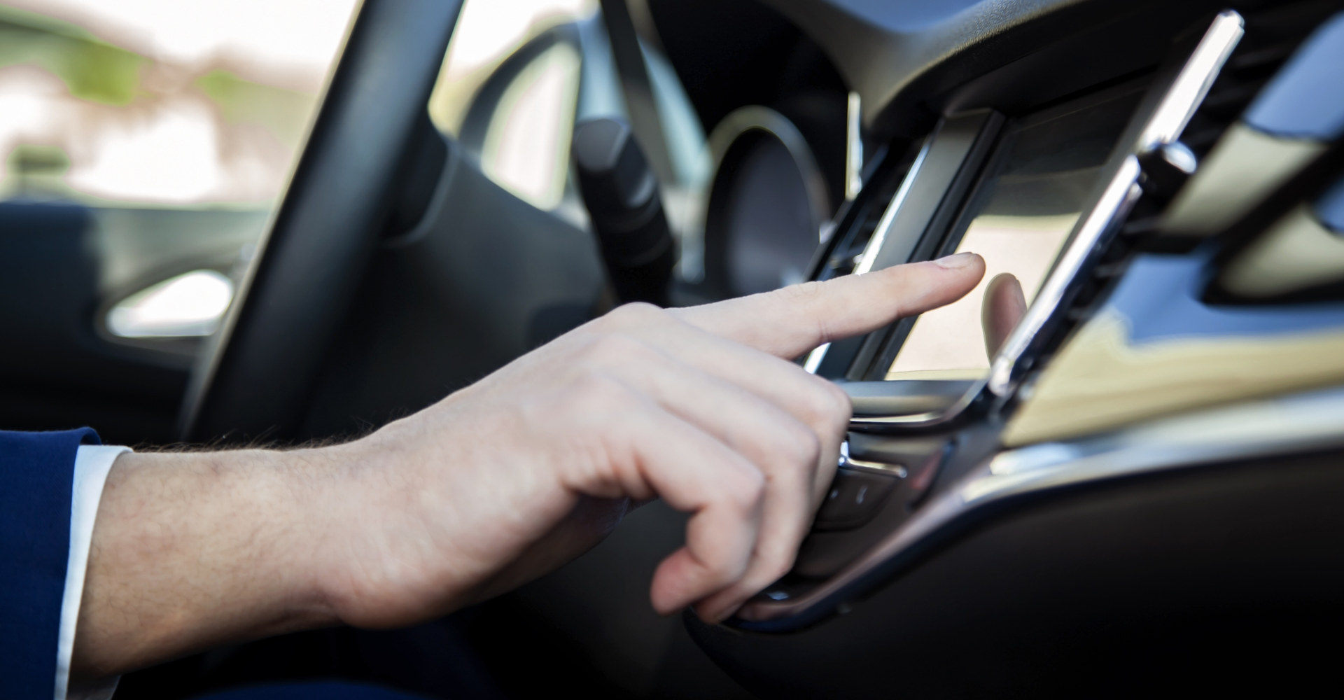 Person tippt im Auto auf das Display des Infotainmentsystems