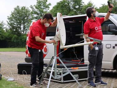Zwei Techniker des Vodafone Instant Network Teams errichten eine Mini-Mobilfunkstation.