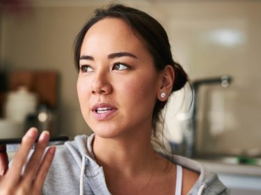 Frau gibt einen Sprachbefehl via Smartphone