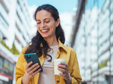 Lächelnde Frau passt auf iPhone die E-Mail-Adresse ihres Apple Accounts an