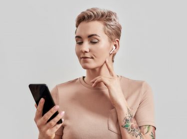 Frau mit Smartphone und AirPods-Kopfhörern