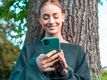 Junge Frau schaut auf ihr Smartphone.