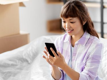 Frau guckt lächelnd auf ihr Smartphone