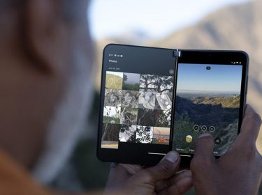 Mann hält Falt-Smartphone Surface Duo 2 vor Berglandschaft