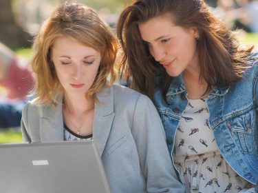 Zwei Frauen im Park gucken auf einen Laptop-Bildschirm
