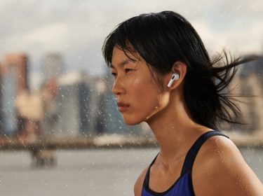 Sportliche Frau trägt AirPods 3 im Freien umgeben von Tropfen