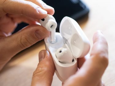 Ein Mann zieht AirPods Pro von Apple aus dem Ladecase.