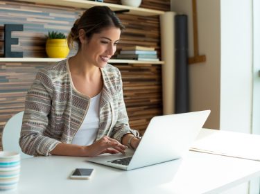 Eine Frau sitzt vor ihrem Laptop.