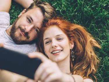 Paar nimmt Selfies mit dem Handy auf.