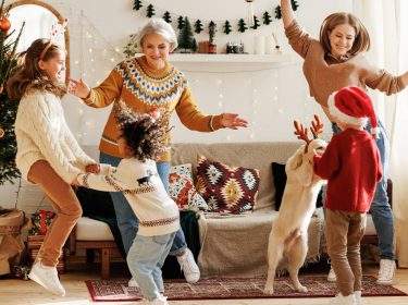 eine Familie aus unterschiedlichen Generationen mit einem Golden Retriever, die alle tanzen
