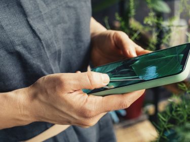 Frau schaut auf einen Hintergrund auf ihrem Handy.