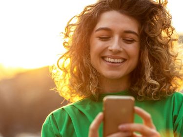 Frau schaut auf ihr iOS-Smartphone.