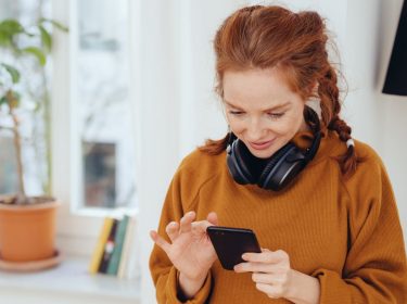 Frau schaut Instagram-Stories am Handy an.